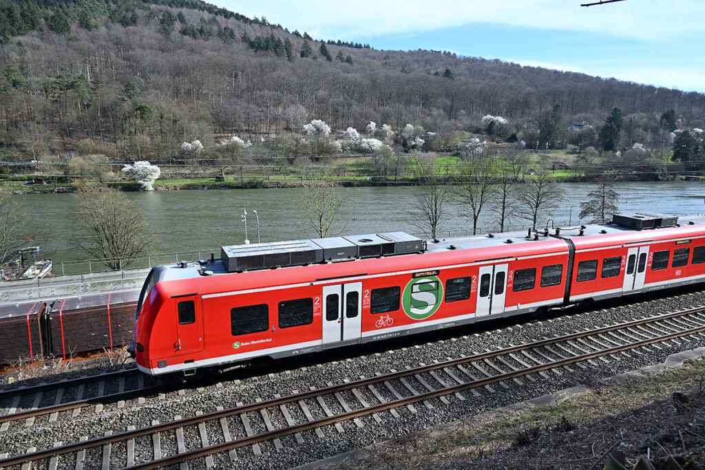 Eine S-Bahn fährt an einem Fluss entlang.