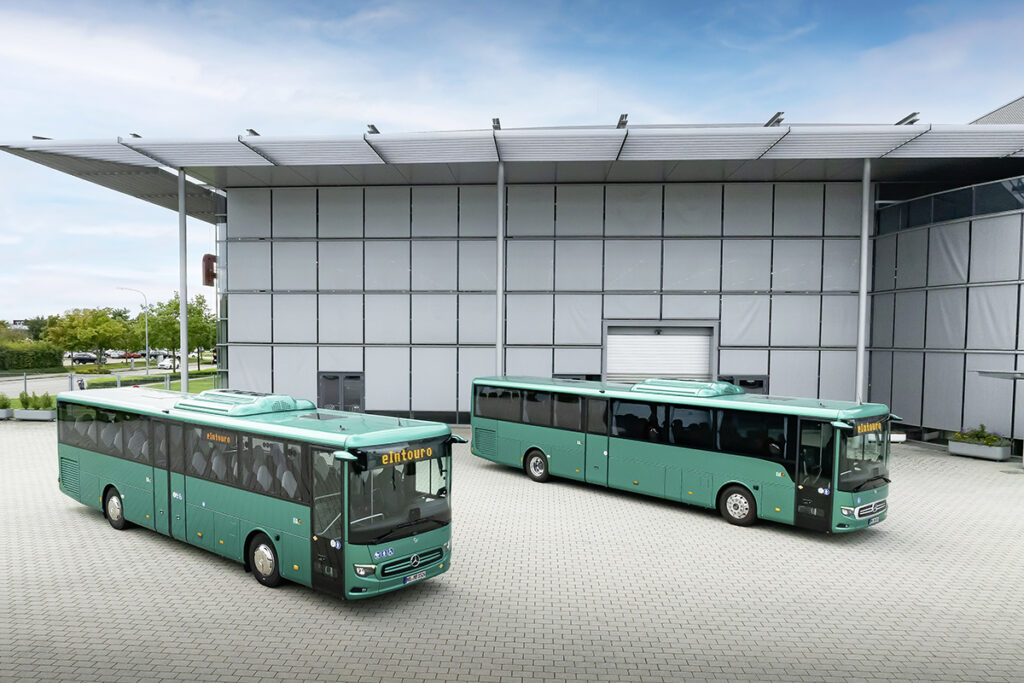 Zwei Busse stehen vor einer Halle.