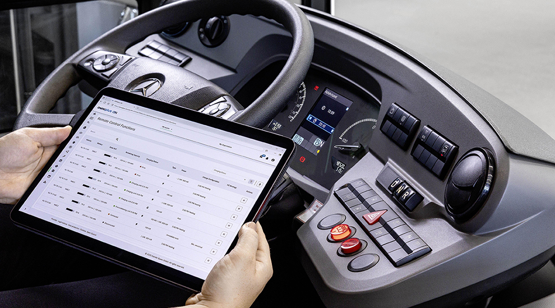 Eine Person hält ein Tablet neben einem Buslenkrad.
