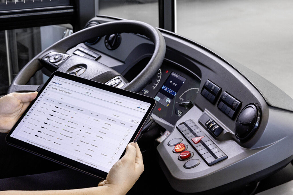 Eine Person hält ein Tablet neben einem Buslenkrad.