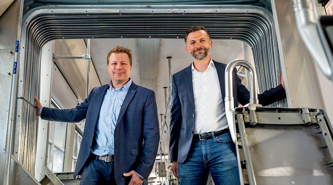 Zwei Personen stehen in einer Straßenbahn.