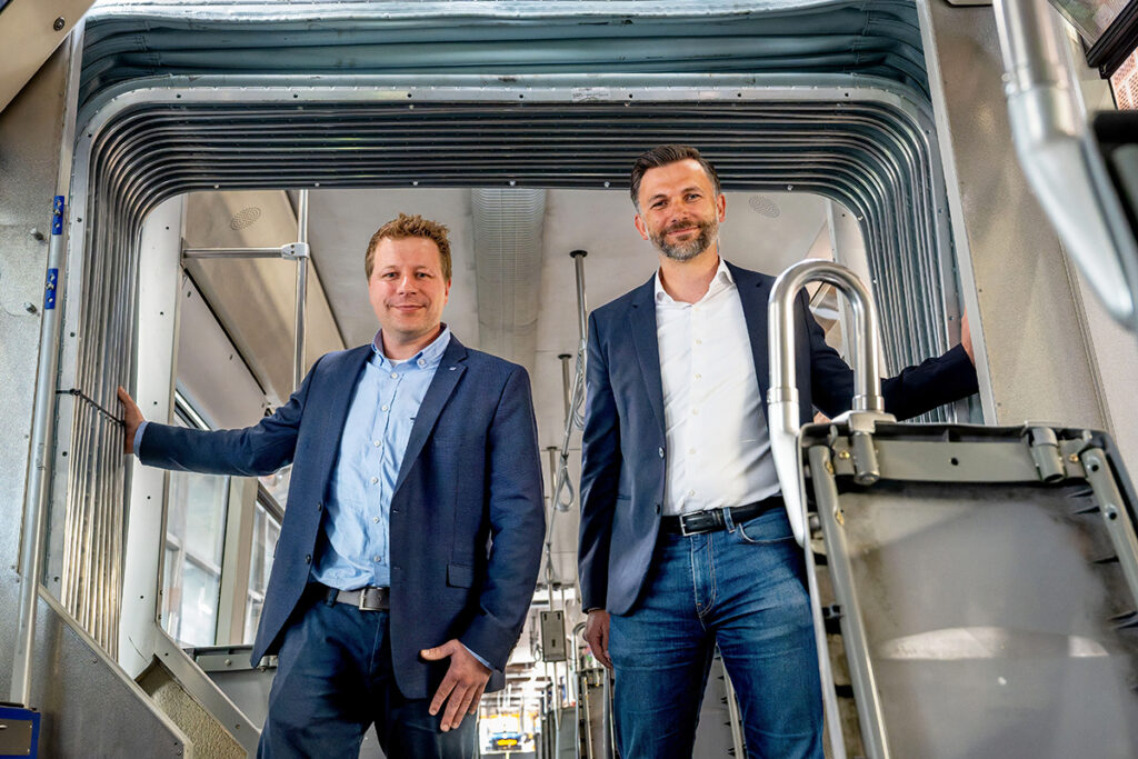 Zwei Personen stehen in einer Straßenbahn.