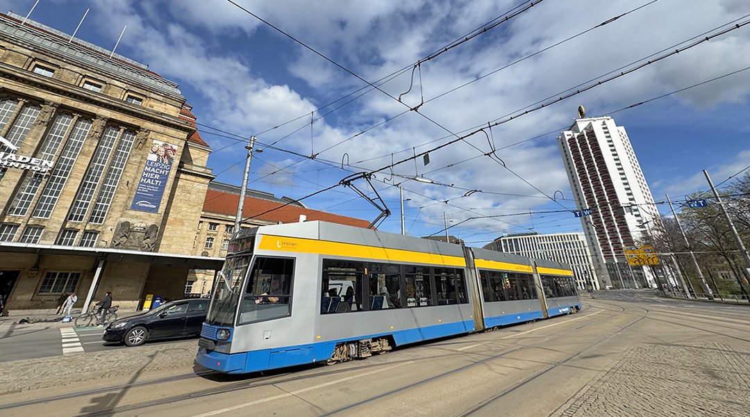 Eine Straßenbahn fährt vor Gebäuden entlang.