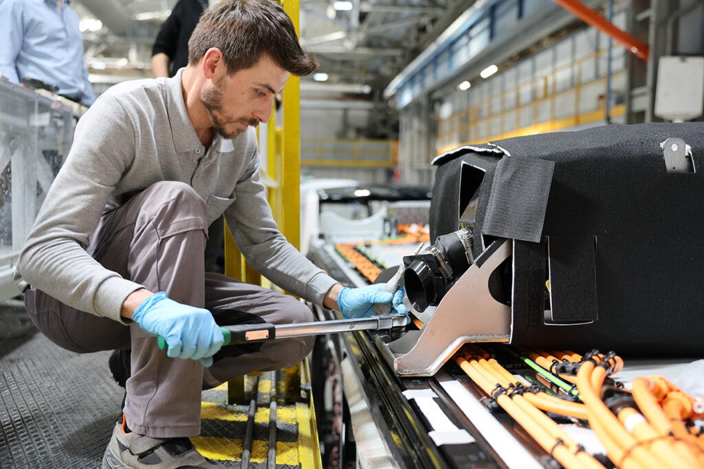 Eine Person arbeitet mit einem Werkzeug an einer Buskomponente.