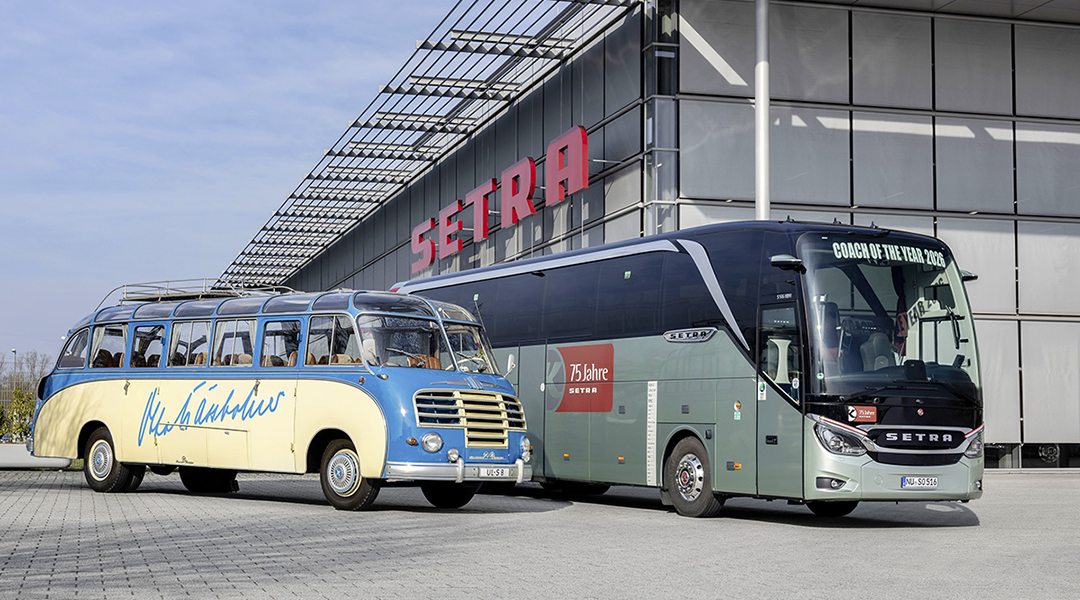 Ein historischer und ein neuer Reisebus stehen vor einer Halle.