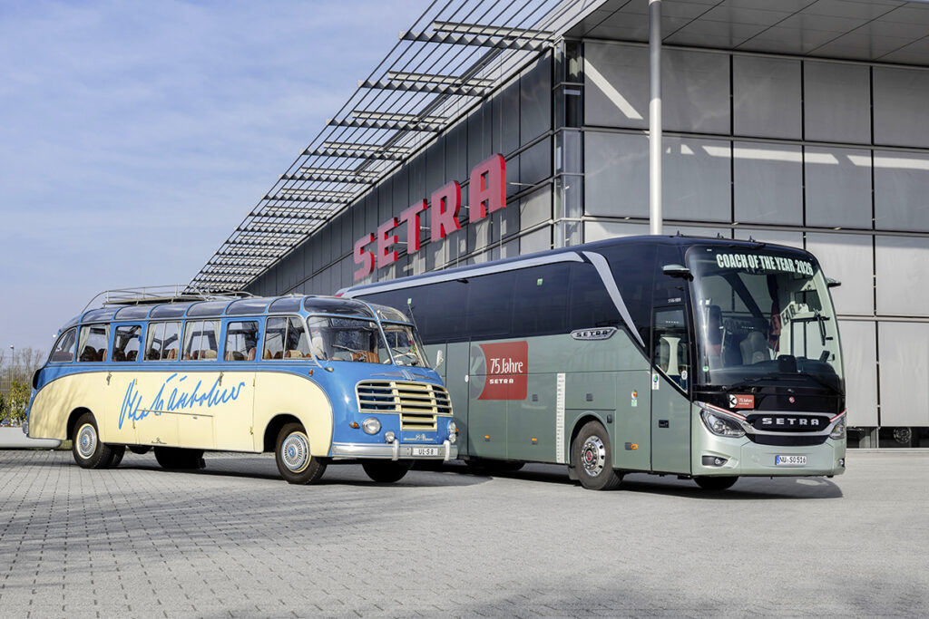 Ein historischer und ein neuer Reisebus stehen vor einer Halle. 
