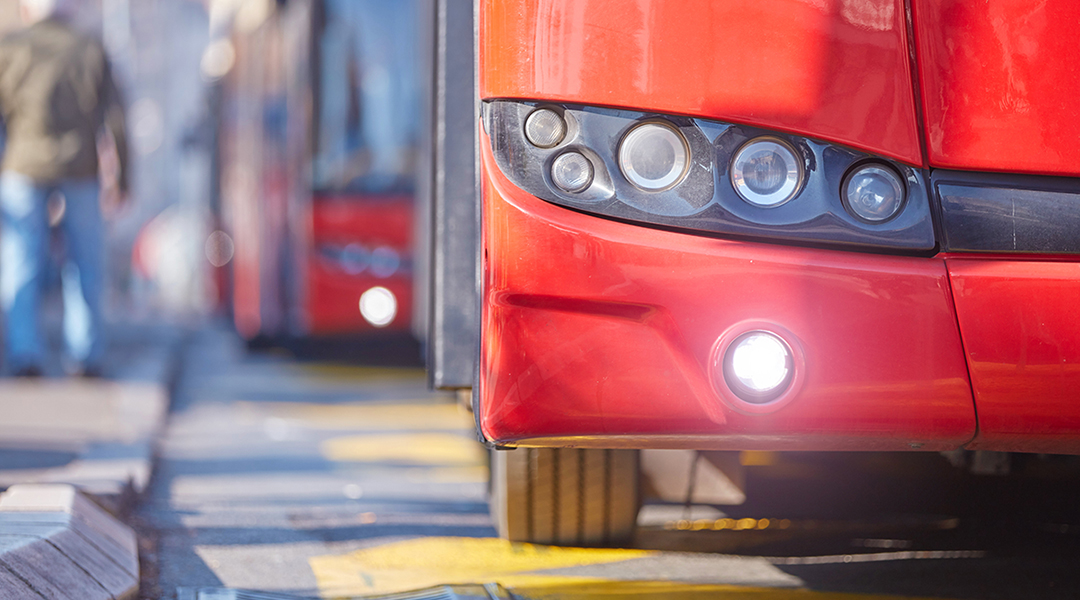 Die Scheinwerfer eines Busse, der an einem Bordstein steht.