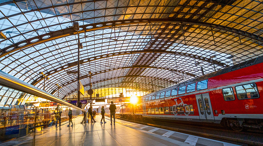 In eine Bahnhofshalle mit einem Zug scheint die Sonne hinein.
