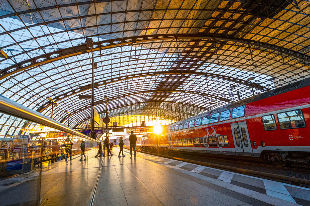 In eine Bahnhofshalle mit einem Zug scheint die Sonne hinein.