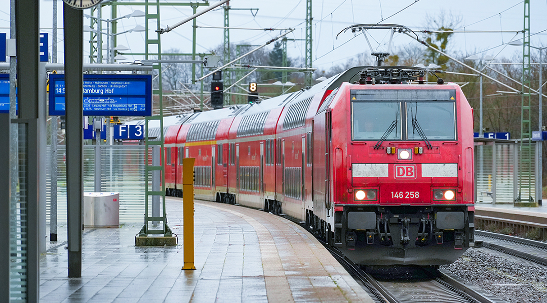 Ein Zug mit Doppelstockwagen fährt an einem Bahnsteig ein.