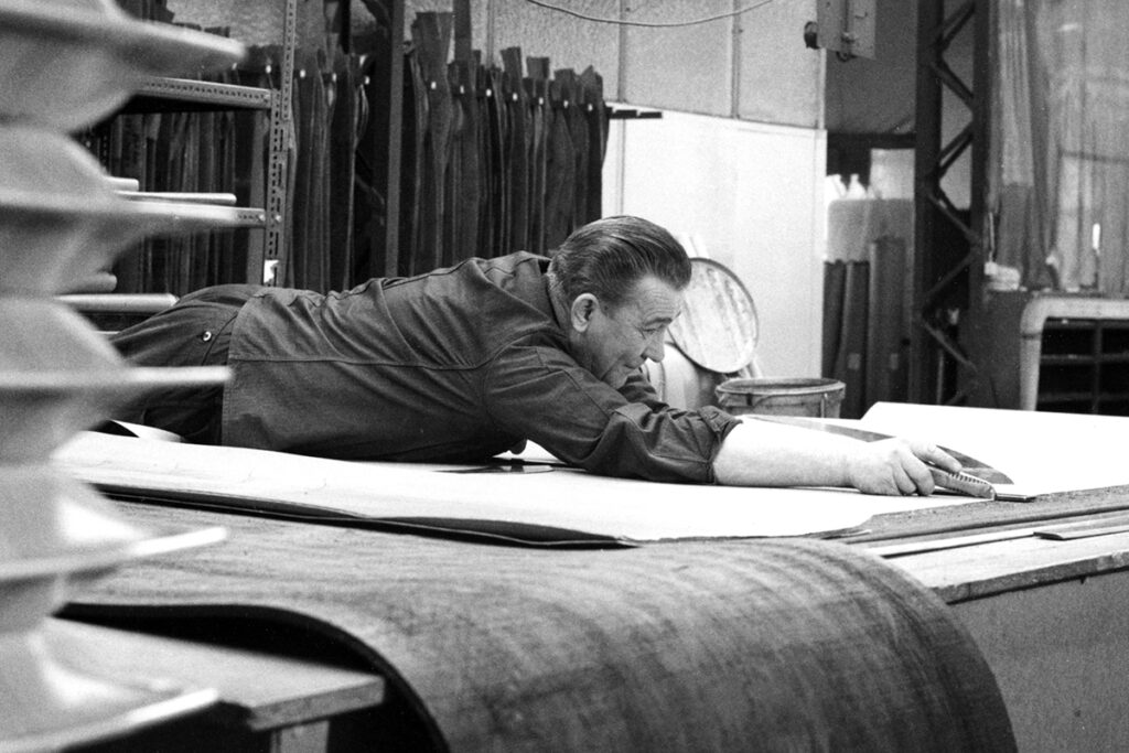 Historisches Bild einer Person, die Stoffe auf einem Tisch mit einem Messer schneidet.