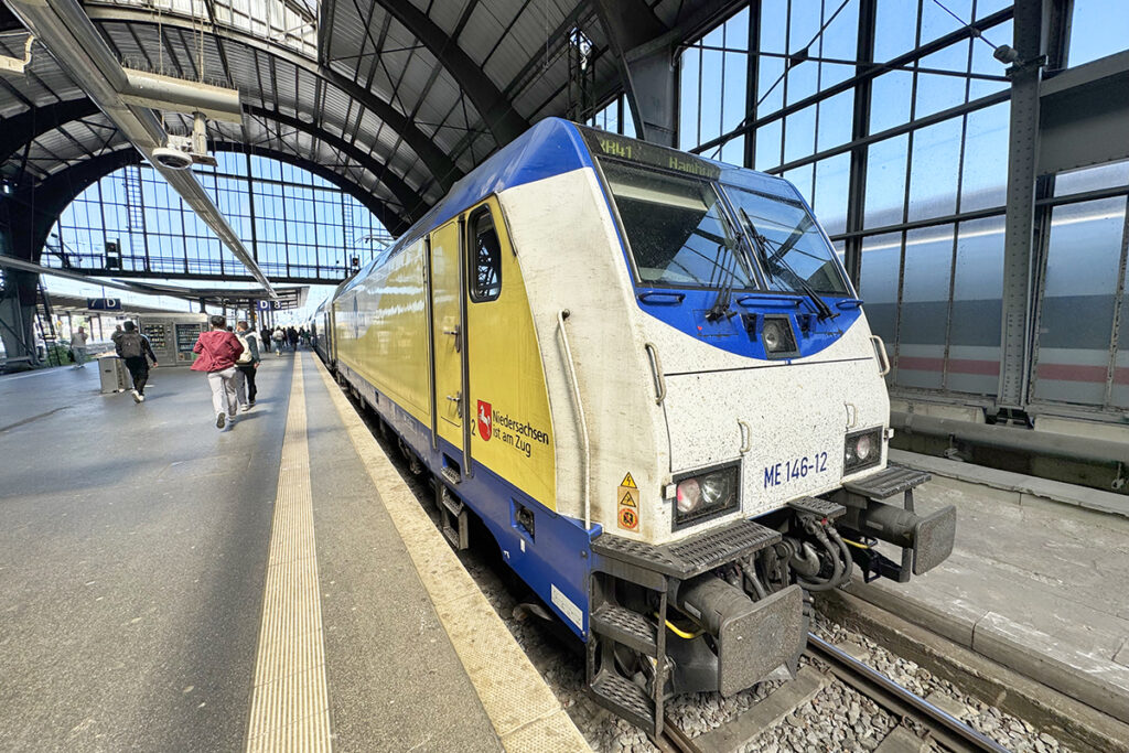 Ein Zug steht in einer Bahnhofshalle an einem Bahnsteig.
