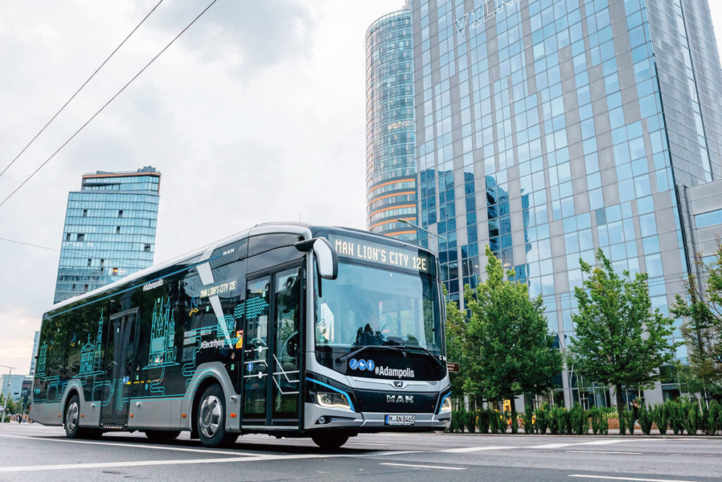 Ein Elektrobus steht vor Hochhäusern.