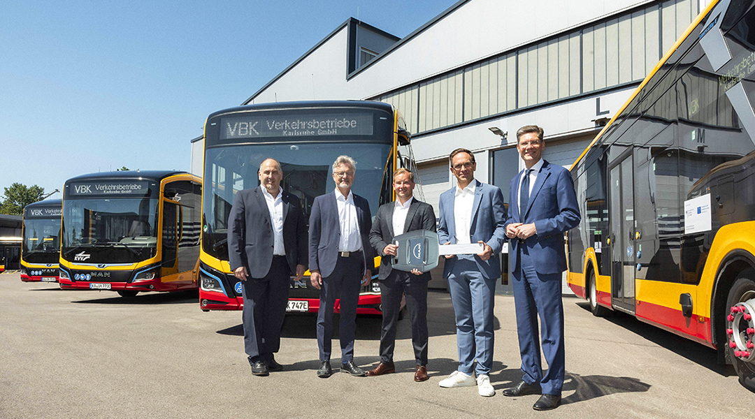 Mehrere Menschen stehen vor neuen Elektrobussen.