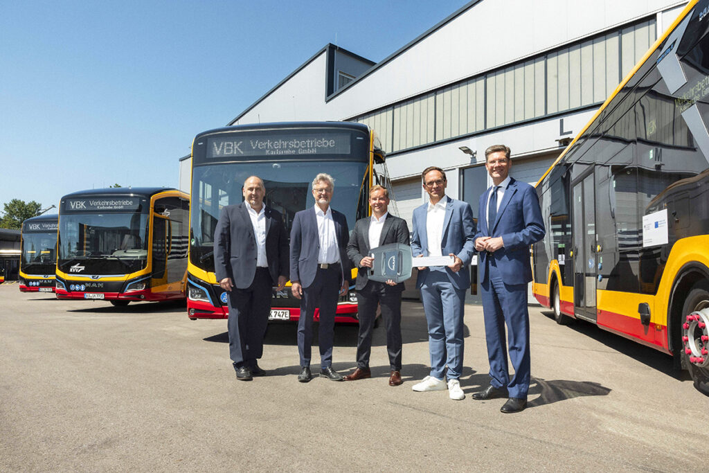 Mehrere Menschen stehen vor neuen Elektrobussen.