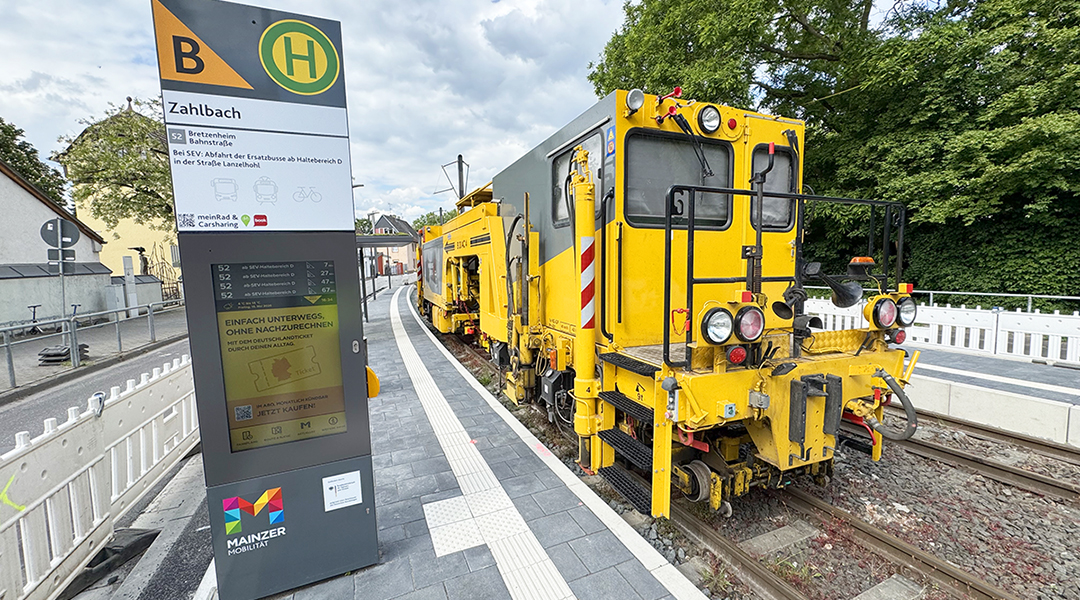 Eine Gleisbaumaschine steht in einer straßenbahn-Haltestelle.