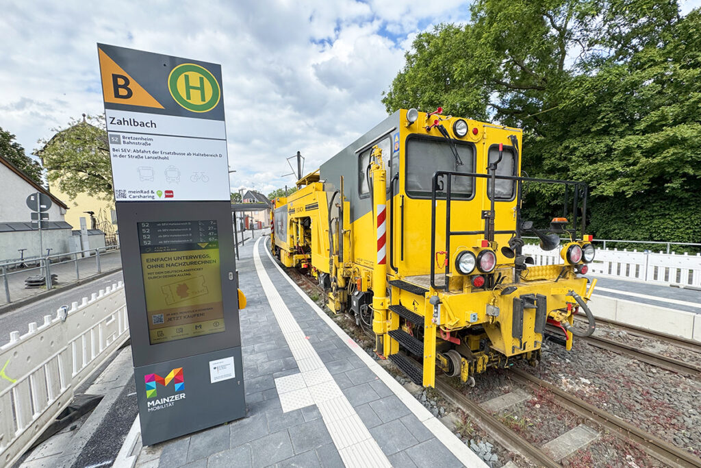 Eine Gleisbaumaschine steht in einer straßenbahn-Haltestelle.