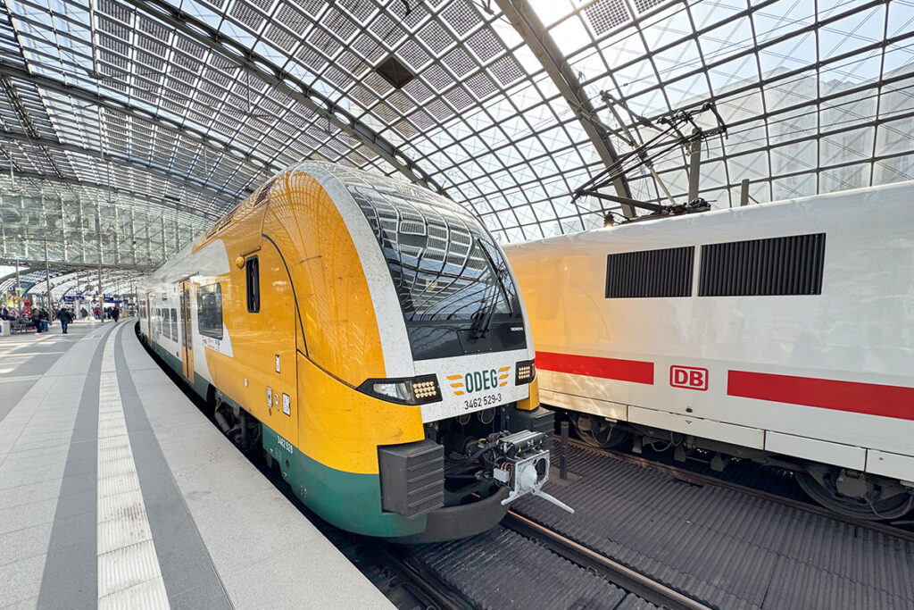 Ein Zug hält in einer Bahnhofshalle an einem Bahnsteig.