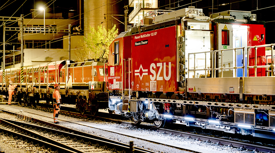 Eine Gleisbaumaschine steht zusammen mit einem Waggon auf einem Gleis.