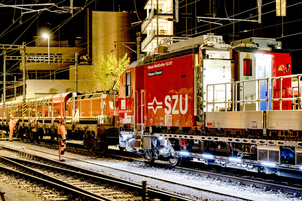 Eine Gleisbaumaschine steht zusammen mit einem Waggon auf einem Gleis.