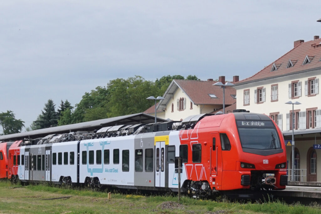 Ein Zug steht in einem Bahnhof vor einem Empfangsgebäude.