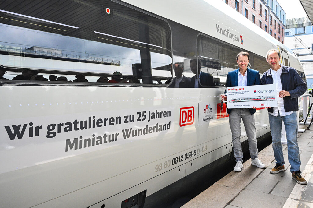 Zwei Personen stehen auf einem Bahnsteig neben einem ICE mit dem Namen Knuffingen.