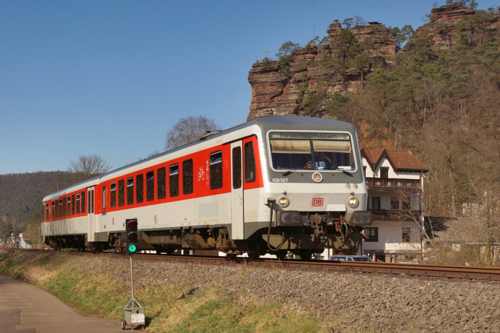 Ein Triebwagen fährt vor einer Felswand entlang.