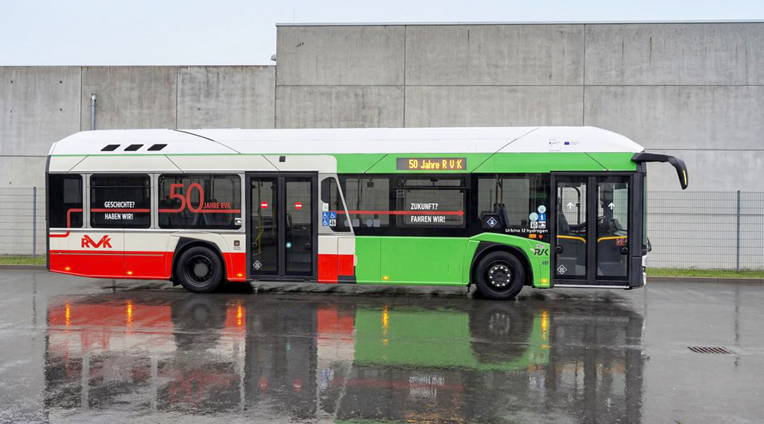 Ein bunt beklebter Bus steht vor einer Mauer im Regen.