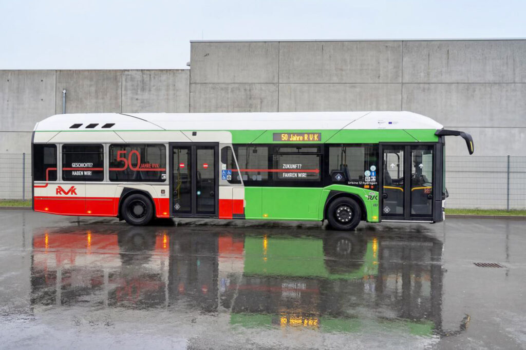 Ein bunt beklebter Bus steht vor einer Mauer im Regen.
