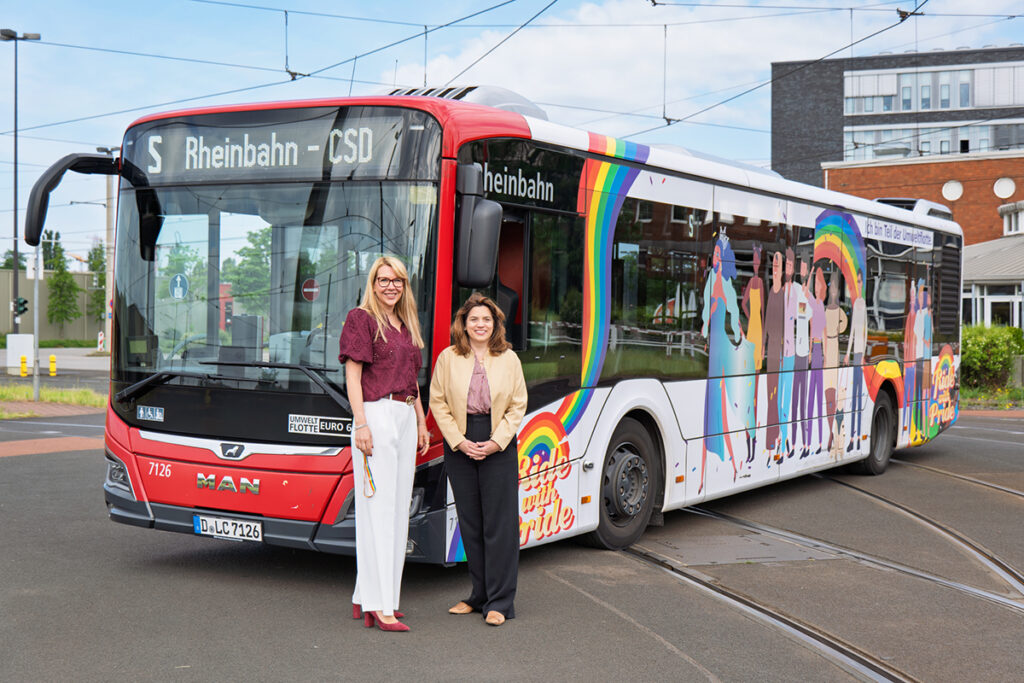 Zwei Personen stehen vor einem bunt beklebten Bus.