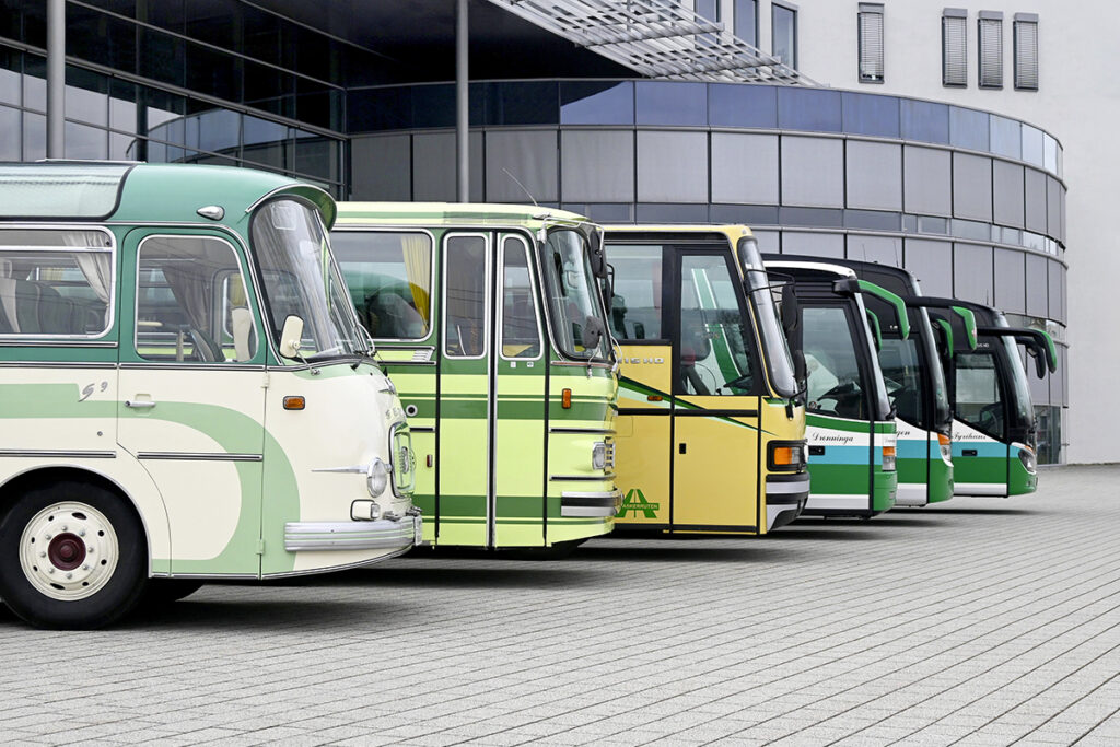 Mehrere Reisebusse stehen vor einer Halle nebeneinander.