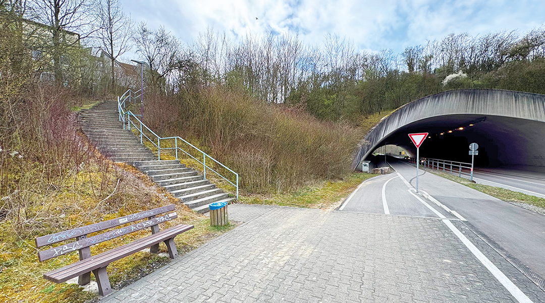 Eine Bank steht auf einem Bahnsteig an einer Bahnstrecke ohne Gleise.
