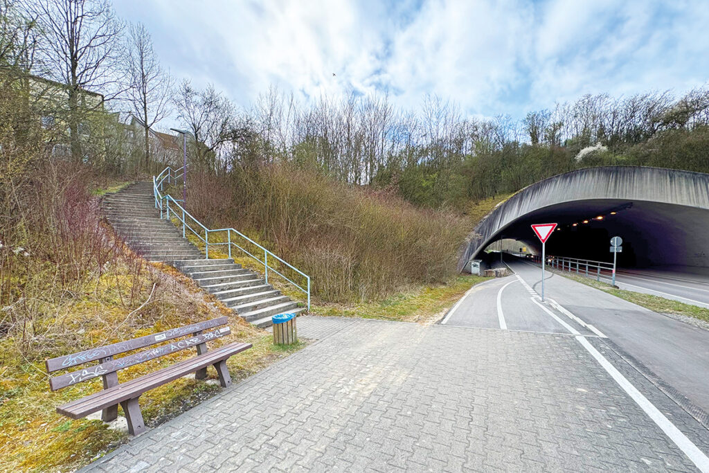 Eine Bank steht auf einem Bahnsteig an einer Bahnstrecke ohne Gleise.
