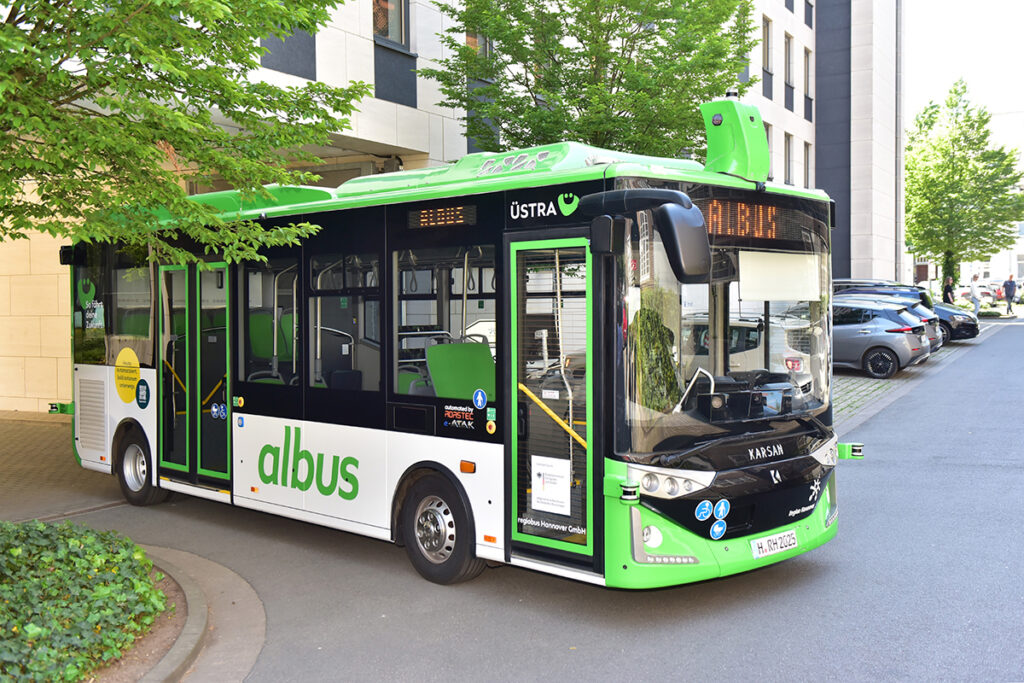 Ein autonomer Bus steht vor einem Gebäude.