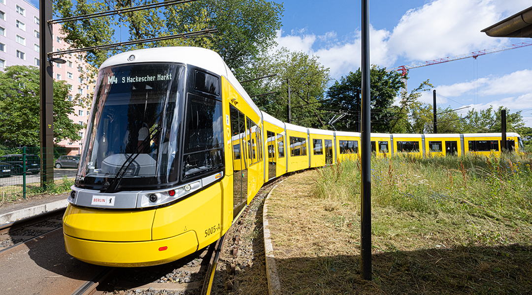 Eine lange Straßenbahn steht in einer Kurve.