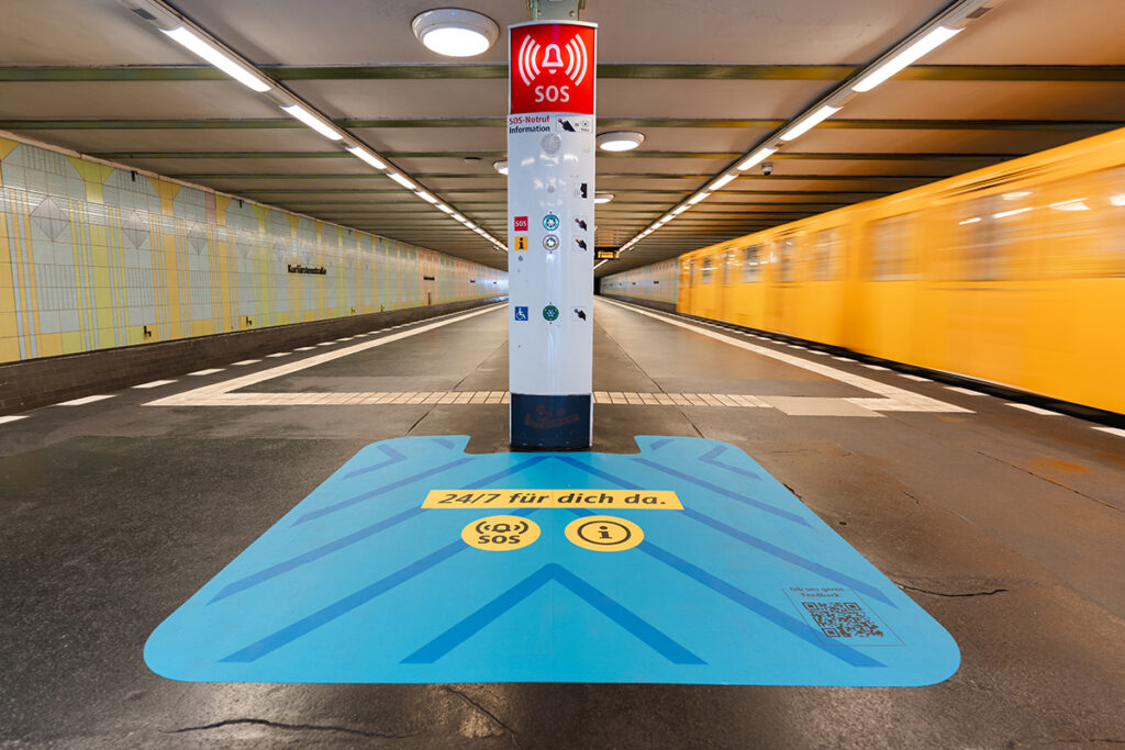 Eine Notrufsäule auf einem Bahnsteig mit einer markierten Fläche davor.