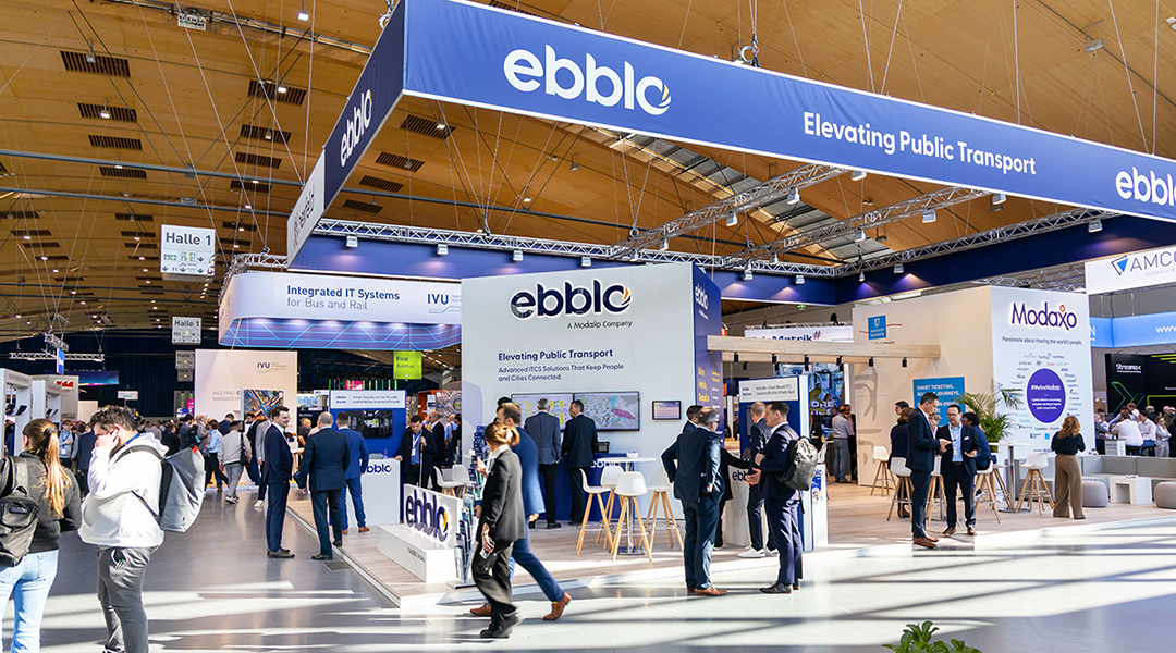 Ein Messestand mit vielen Leuten in einer Halle.