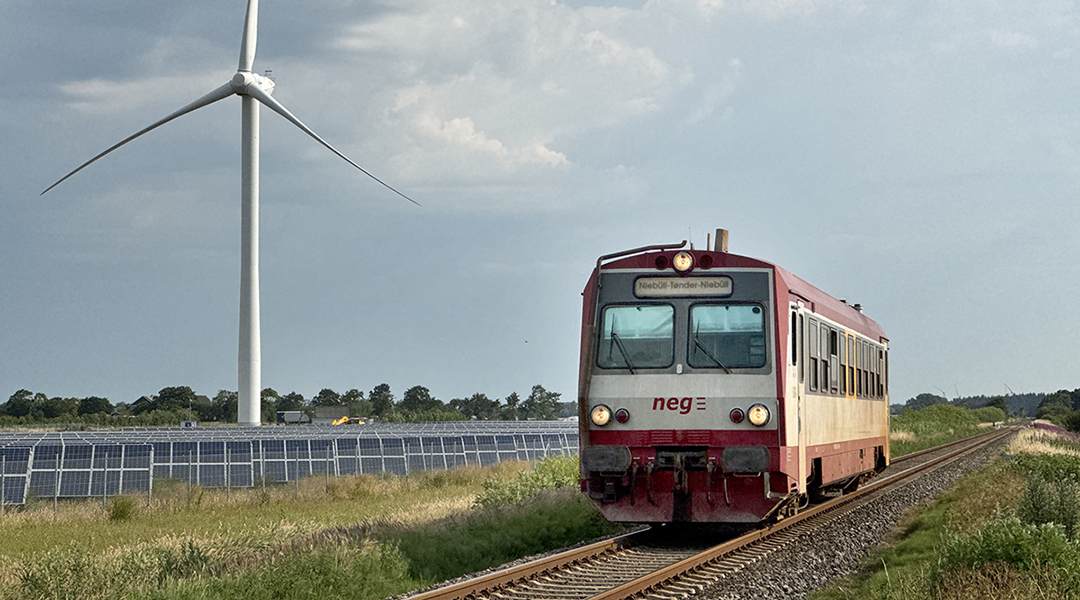 Ein Zug fährt an einem Windrad vorbei.