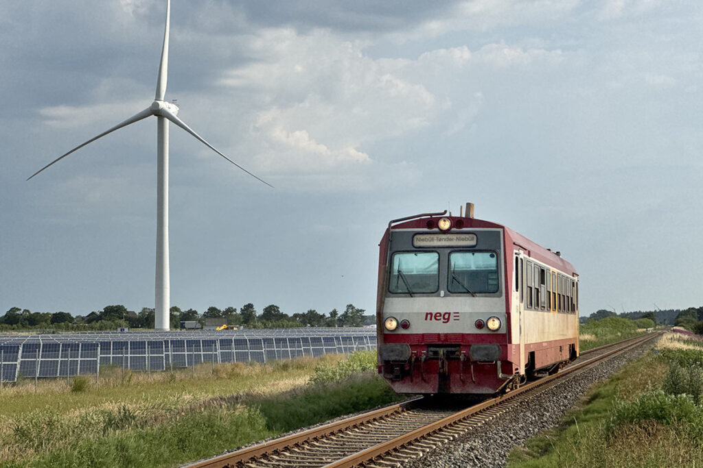 Ein Zug fährt an einem Windrad vorbei.
