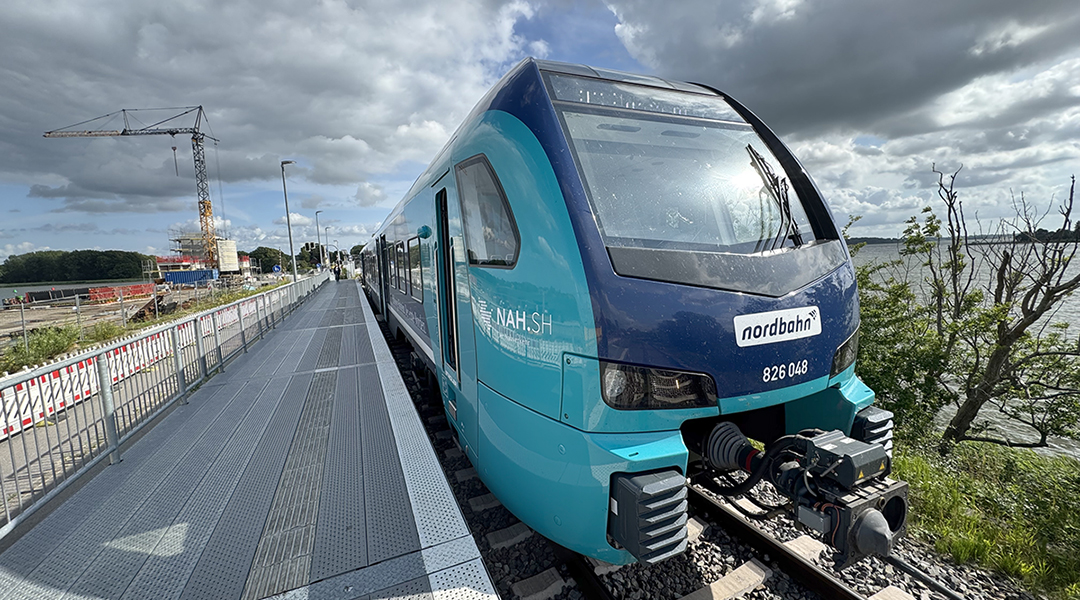 Ein Akkuzug steht an einem Bahnsteig oder einer Baustelle.