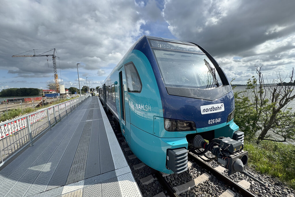 Ein Akkuzug steht an einem Bahnsteig oder einer Baustelle.