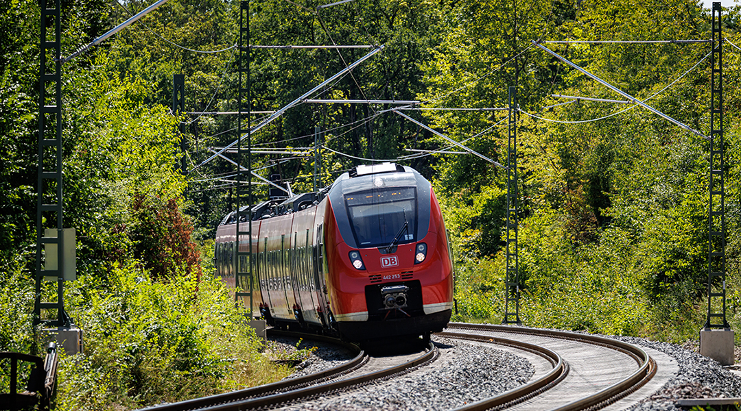 Ein Zug fährt auf einer zweigleisigen Strecke durch einen Wald.