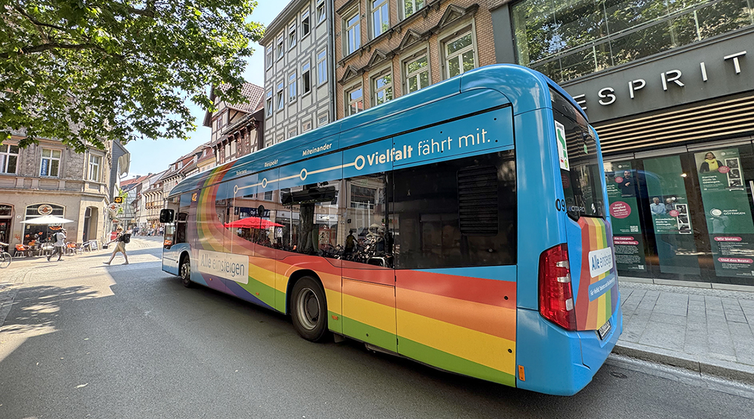 Ein Bus steht an einer Haltestelle vor Häusern.