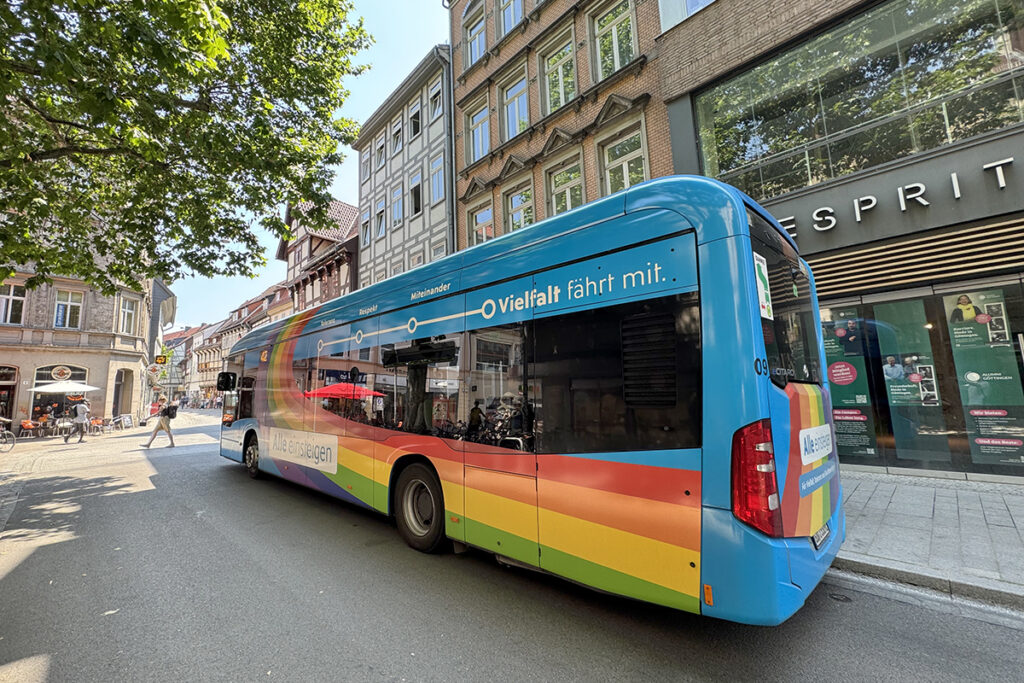 Ein Bus steht an einer Haltestelle vor Häusern.