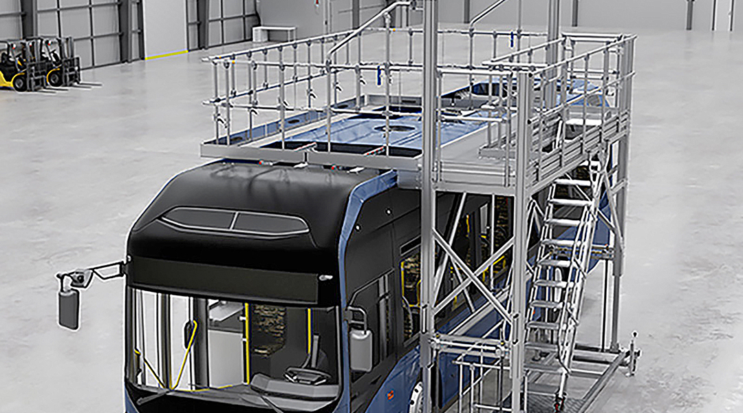 Ein Bus steht neben einer Arbeitsbühne in einer Halle.