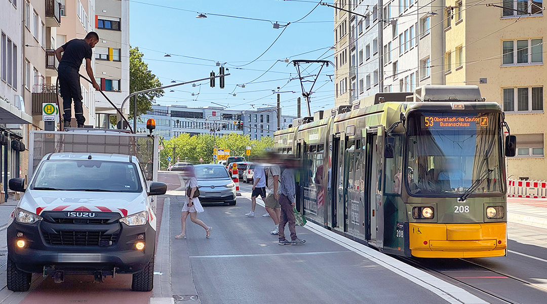 Eine Straßenbahn hält an einer Haltestelle, Personen steigen ein und aus.
