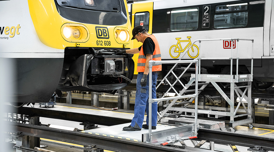 Eine Person steht auf einer Arbeitsplattform vor einem Zug.