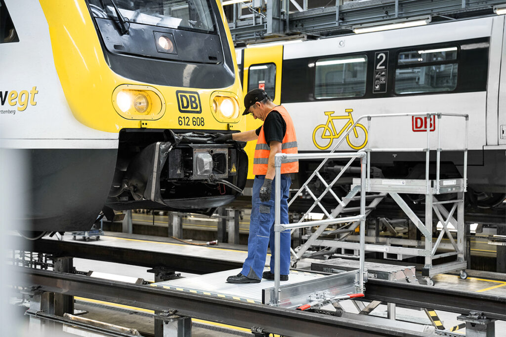 Eine Person steht auf einer Arbeitsplattform vor einem Zug.