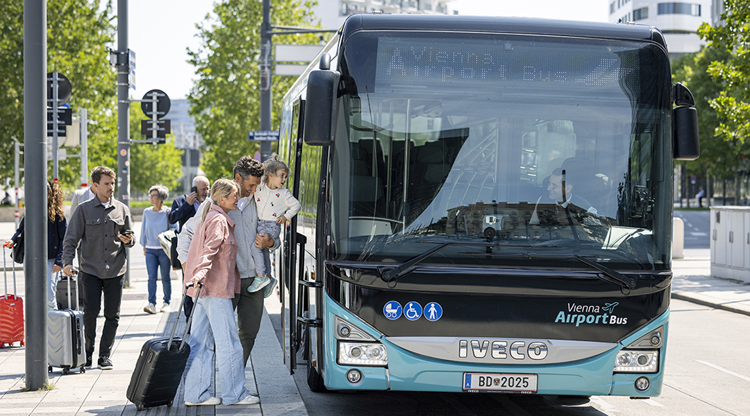 Neben einem Bus stehen Personen, die einsteigen.