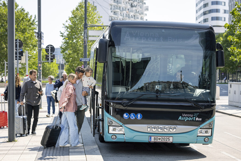 Neben einem Bus stehen Personen, die einsteigen.